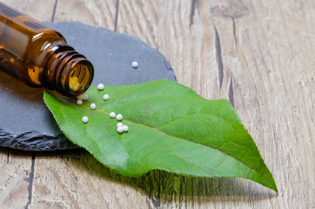 Leaf with vial of homeopathic pellets